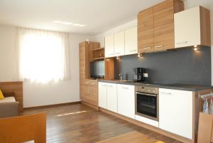 崔聂斯Appartament Eichnerhof的厨房配有白色橱柜和木地板。
