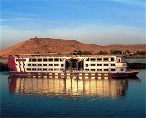 卢克索Cleopatra Nile 5 Star Trek Cruise every Friday from Aswan for 3 Nights Every Monday from Luxor 4 Nights的水中一艘大船,底下是山