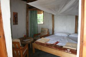 卡巴莱Amasiko Homestay Lake Bunyonyi的卧室配有一张床和一张桌子及椅子