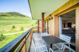 拉普德兹Residence Hameau de Clotaire Alpe d'Huez - by EMERALD STAY的木制阳台配有桌椅