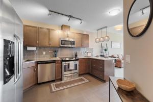 卡尔加里Heart of Downtown Calgary Spacious Luxury Condo with Stunning Views and Premium Amenities的厨房配有木制橱柜和不锈钢用具