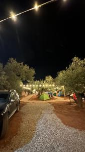 AyvacıkVamos Camping的夜间停车场,有帐篷和汽车