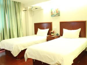舟山格林豪泰浙江省舟山市新城商务酒店的配有白色床单的酒店客房内的两张床