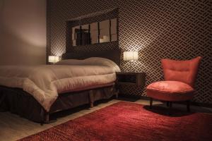 瓜达拉哈拉普拉迪诺博览会酒店的一间卧室配有一张带镜子和红色椅子的床
