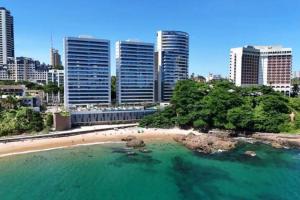 萨尔瓦多Apartamento Salvador BC1309 Pé na Areia Vista Mar Barra Ondina的城市前方的海滩,有高楼