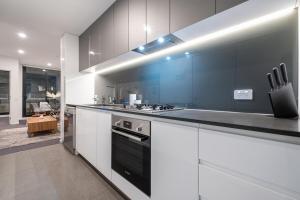 墨尔本Pleasant &bright 2br2ba Apt Footscray Pool的厨房配有白色橱柜和黑炉灶烤箱。