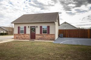 WaynesvilleTiny Home With Hot Tub Near Ft Leonard Wood!的一座带红色门和栅栏的房子