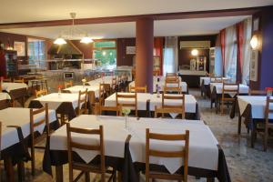 奥尔迪诺拉普朗达酒店的用餐室配有白色的桌子和木椅