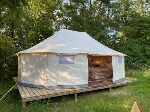 马尔欣Glamping im Gutspark的田野上带木平台的白色帐篷