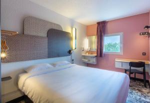 DéolsB&B HOTEL Châteauroux A20 L'Occitane的卧室配有白色的床、书桌和窗户。