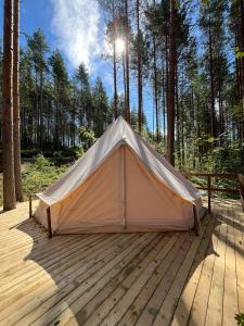 萨翁林纳Alaska Glamping Linnansaari的树林木甲板上的帐篷