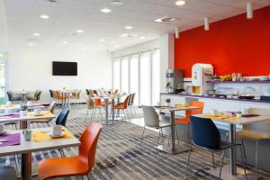 科尔马科尔马会展中心康福特茵酒店的一间带桌椅和红色墙壁的餐厅