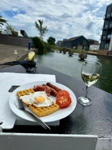 切姆Unique Narrowboat in Town Centre Chelmsford Essex的一小盘早餐食品和一杯葡萄酒