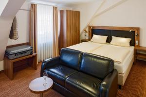 贝格施特拉瑟黑彭海姆格德纳恩格尔酒店餐厅的酒店客房配有一张床和一张皮沙发