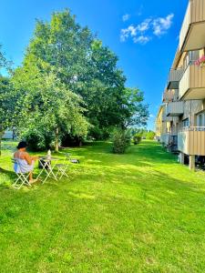 卡尔马Nice guest room apartment within walking distance to Kalmar central station的坐在建筑物旁的院子里的椅子上的女人