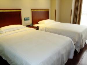 合肥格林豪泰安徽省合肥市高铁南站包河大道包河区政府商务酒店的配有白色床单的酒店客房内的两张床