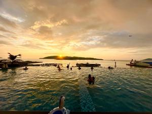 哥打京那巴鲁Sunset Seaview Vacation Condos @ Jesselton Quay的日落时分水面上的一群人