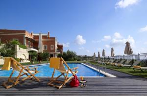 阿卡尼斯卡塔拉加里乡村套房酒店的一组椅子和遮阳伞,位于游泳池旁