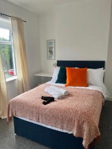 巴里Spacious Barry Island House Sleeps 8 Dog Friendly Family with Garden Space and Breakfast Included的一张带橙色和白色枕头的床和窗户