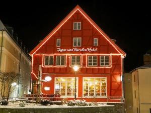 卑尔根Märchenhotel的一座红色的建筑,晚上有标志