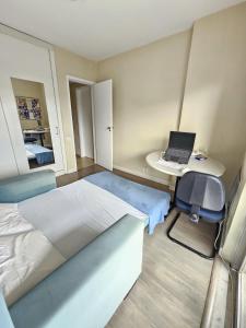 里约热内卢Quarto Aconchegante的一间卧室配有一张床和一张带笔记本电脑的书桌
