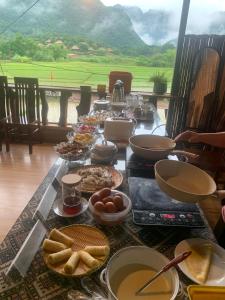 枚州县Green Homestay Mai Chau的一张长桌,上面有食物,享有美景