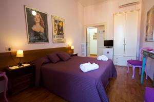 罗马拉特兰诺酒店的一间卧室配有一张紫色床和两条毛巾