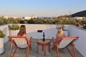 普拉提伊亚洛斯西弗诺斯埃德姆酒店的两名妇女在阳台上坐在椅子上,并享用一瓶葡萄酒