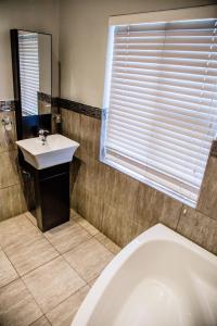 莱迪史密斯Nauntons Guest House & Wedding Venue的带浴缸、水槽和窗户的浴室
