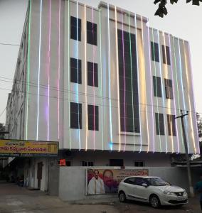 巴德拉恰拉姆Sri Kakateeya Grand Residency Bhadrachalam Hotel Residency Stay Rooms的前面有停车位的建筑