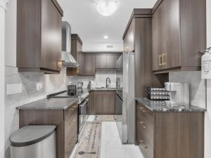 温莎Stylish 2-Bedroom Apartment In Downtown Windsor的厨房配有木制橱柜和不锈钢冰箱。