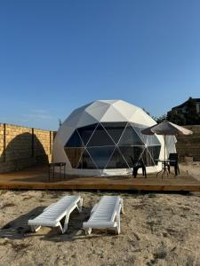 巴库Glamping Baku的一座带两个长凳和一把伞的大型圆顶建筑