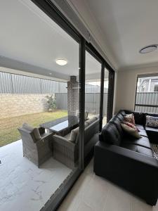 Narellan4 bedrooms beautiful home的客厅配有黑色真皮沙发和玻璃门