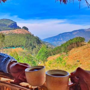 蒙纳Roamrustic Camp Vattavada的两杯酒坐在桌子上,享有美景