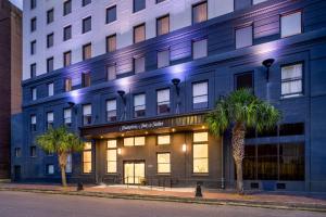 新奥尔良Hampton Inn & Suites New Orleans Canal St. French Quarter的一座蓝色的建筑,前面有棕榈树