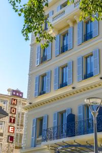 尼斯Hôtel & Appartements Monsigny的白色的大建筑,拥有蓝色的窗户和街边灯光