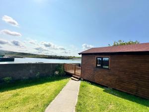 Malin HeadCosy Portmor Log Cabin- Sea views, Deck & Relaxation的水体旁有通道的建筑物