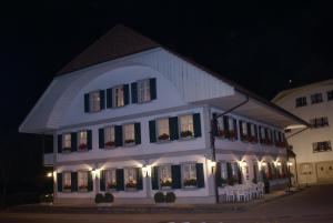 Melchnau加斯索夫鲁汶酒店的一座白色的大建筑,晚上配有桌椅