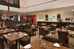 沃特斯道克牛津华美达酒店的一间带木桌椅的餐厅和一间酒吧