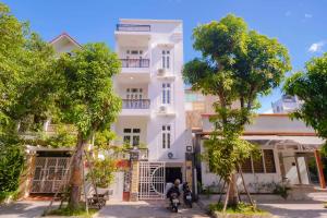 顺化Mô Tê Homestay 2 gần Chợ Đông Ba, Cung Đình Hoàng Thành Huế的前面有两人骑摩托车的白色建筑