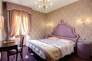 威尼斯多姆斯卡瓦尼斯酒店的一间卧室配有一张床、一张桌子和一个吊灯。