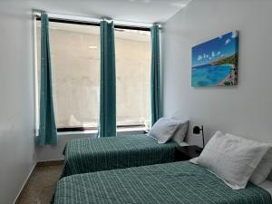 檀香山2BR Downtown High Ceiling Free Parking and WiFi的一间卧室设有两张床,窗户设有绿色窗帘