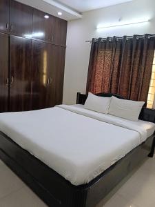 海得拉巴GAYATHRI HEIGHTS SERVICED APARTMENTS & APARTMENT HOTEL In HYDERABAD的一间卧室配有一张带木制橱柜的大床