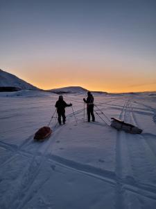 KjøllefjordOvernatting Kjøllefjord, Hybelleilighet med kjøkkenkrok og eget bad的两个人在雪地里滑雪,带雪橇