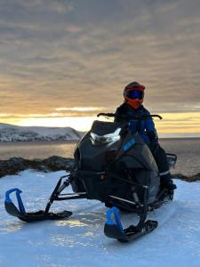 KjøllefjordOvernatting Kjøllefjord, Hybelleilighet med kjøkkenkrok og eget bad的一个人坐在雪地里的雪地车上