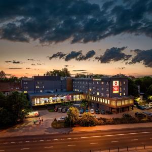 奥尔什丁Best Western Plus Hotel Olsztyn Old Town的黄昏时停泊在停车场的大楼