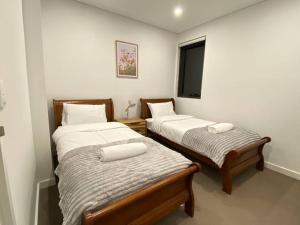 悉尼KozyGuru Campsie Brandnew 3 Room Home Parking的配有电视的客房内的两张单人床