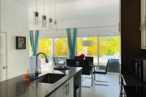 Long Bay HillsModern villas at Grace Bay, Turks and Caicos Islands的厨房配有水槽和桌椅