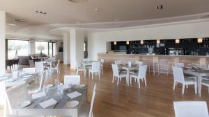 埃尔戈尔多瓦尔德卡尼亚斯高尔夫文奇酒店的一间设有白色桌椅的餐厅和一间酒吧