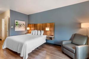 Extended Stay America Premier Suites - Belgrade - Bozeman - Yellowstone Airport的卧室配有一张白色大床和一把椅子